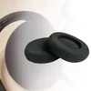 Two black foam ear pads are placed on a blurred background of a headphone. Produktbild-Vorschau