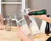 A person is using a cordless hot glue gun on a clear glass vase, with other vases in the background. Produktbild-Vorschau