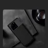 A black smartphone case with a sliding camera cover is placed on a textured gray surface, next to a black coffee cup. Voir les images du produit