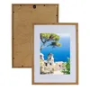 A framed picture of a coastal village scene with a tree in the foreground. Produktbild-Vorschau