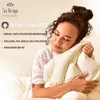 A woman is embracing a cream-colored comforter, appearing comfortable and relaxed. Produktbild-Vorschau