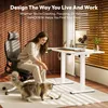 A woman is sitting in an office chair and playing with her cat next to a standing desk. Produktbild-Vorschau