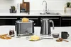 A kitchen counter with a toaster, kettle, bread, jam, butter, and coffee. Anteprima dell’immagine prodotto