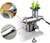 A manual juicer is shown on a table, with celery stalks in the top hopper and pulp being extracted from the front. Produktbild-Vorschau