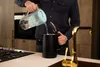 A person is pouring filtered water from a pitcher into a black electric kettle in a kitchen. Náhľad obrázku produktu