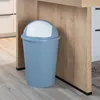 A pastel blue trash can with a white lid sits on a light gray wooden floor next to a wooden cabinet. Produktbild-Vorschau