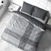 A neatly made bed with a duvet and pillows, set in a bedroom with a nightstand and a window. Produktbild-Vorschau