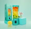 A teal colored portable blender filled with colorful fruit slices, placed next to its packaging and a lemon slice, on a light teal and white background with a flower. Náhľad obrázku produktu