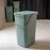 A green trash can with a lid and handle is shown in a kitchen setting. Náhled obrázku produktu