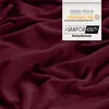 A close-up of a burgundy fabric with a label indicating certifications. Produktbild-Vorschau