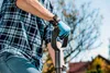 A person wearing a plaid shirt and blue gloves is holding a shovel. Náhľad obrázku produktu