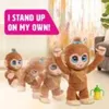 Several toy monkeys are lined up, with one in the foreground standing with arms raised. A small yellow and green bottle is next to it. The background is a softly lit room. Produktbild-Vorschau