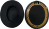 Two black ear pads for headphones, one showing the fabric side and the other showing the attachment side with a brown adhesive strip. Produktbild-Vorschau