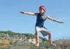 A young person is slacklining outdoors with trees and hills in the background. Produktbild-Vorschau