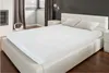 A white fitted sheet is placed on a white leather bed in a bedroom setting. Produktbild-Vorschau