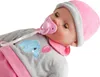 A close-up shot of a baby doll wearing a pink hat and gray outfit with a blue elephant and pink balloon embroidered on it. The doll has a pink pacifier in its mouth. Náhľad obrázku produktu