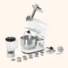 A white kitchen appliance with multiple attachments is displayed against a light beige background. Produktbild-Vorschau