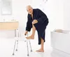 An elderly man in a bathroom, using a shower stool to shave his leg. Produktbild-Vorschau