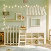 A child's bedroom with a white loft bed designed like a house, decorated with string lights and featuring shelves for storage. Náhľad obrázku produktu