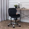 A black office chair is placed next to a wooden desk in a room with curtains and a wall. Produktbild-Vorschau