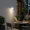 An outdoor patio at night, with a wall-mounted light illuminating a table set for two. Produktbild-Vorschau