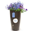 A brown rain barrel filled with blue and purple flowers, with a tag indicating "Made in Europe" and a capacity of "240 L". Produktbild-Vorschau