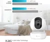 A white security camera is shown in the foreground, with a blurred bedroom scene in the background. Text overlays describe video storage and bandwidth comparisons. Voir les images du produit