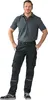 A man wearing work pants and a polo shirt, standing with his hands in his pockets. Anteprima dell’immagine prodotto