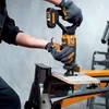 A person wearing gloves is using a cordless reciprocating saw to cut a piece of wood on a workbench. Voir les images du produit