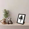 A black picture frame with a silhouette of a ballerina is displayed on a shelf next to stuffed toys and a plant. Náhled obrázku produktu