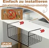 A black wire storage basket is shown hanging under a white desk. A laptop, coffee cup, and pencil are on the desk. Produktbild-Vorschau
