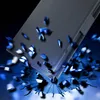 A dark, abstract background with blue light effects, featuring a black phone case that appears to be shattering or exploding into blue and white fragments. Náhled obrázku produktu