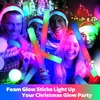 A group of friends in Santa hats are holding and smiling with LED foam glow sticks at a Christmas party. Náhled obrázku produktu