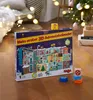 A 3D advent calendar is placed on a wooden floor in a festive setting with a Christmas tree and lights in the background. Voir les images du produit