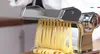 A close-up shot of a pasta machine making fresh pasta. Produktbild-Vorschau