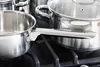 A close-up shot of stainless steel pots and pans on a black gas stove. Anteprima dell’immagine prodotto