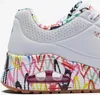 A close-up view of the side and heel of a white SKECHERS sneaker with a colorful graffiti-style print on the sole and collar. Náhled obrázku produktu