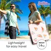 A couple on a beach with palm trees and the ocean in the background, carrying beach mats. Produktbild-Vorschau