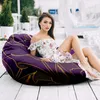 A woman is sitting on a bean bag chair on a wooden deck. Náhled obrázku produktu