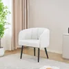 A white fluffy armchair with black legs sits on a light-colored rug in a room with beige curtains and a plant. Produktbild-Vorschau