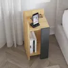 A modern nightstand next to a bed, with a phone charging on top and books on the shelf. Produktbild-Vorschau