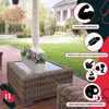 A patio scene with a wicker coffee table holding a white planter filled with pink flowers. The background shows a house and a lawn. Anteprima dell’immagine prodotto