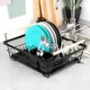 A dish drying rack filled with dishes, glasses, and cutlery, placed on a kitchen counter next to a sink and faucet. Náhled obrázku produktu