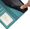 A close-up view of the interior of a teal-colored wallet case, with a hand holding a black phone case. Náhled obrázku produktu