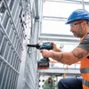 A construction worker using a cordless impact wrench on a metal structure. Podgląd zdjęcia produktu