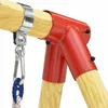 A close-up view of a red metal swing set connector attached to a wooden beam, with a carabiner and rope hanging from it. Podgląd zdjęcia produktu