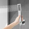 A hand holding a silver shower head with water spraying out, in a tiled bathroom. Podgląd zdjęcia produktu