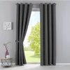 A dark gray curtain is tied back with a fabric tie, revealing a bright green tree and blue sky outside a window. Produktbild-Vorschau