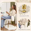 A woman is applying makeup while sitting on a white chair with gold legs in a room. Náhľad obrázku produktu
