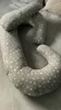 A grey pregnancy pillow with white stars is laid out on a grey surface. Voir les images du produit